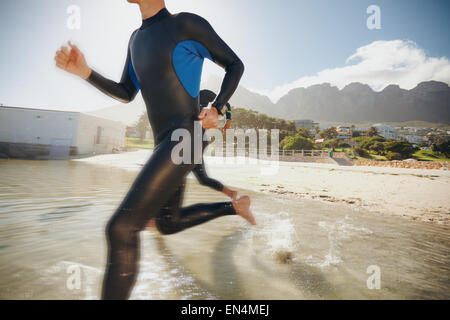Immagine di due triatleti precipitando nell'acqua. Atleta che corre in acqua e di formazione per un triathlon. Foto Stock