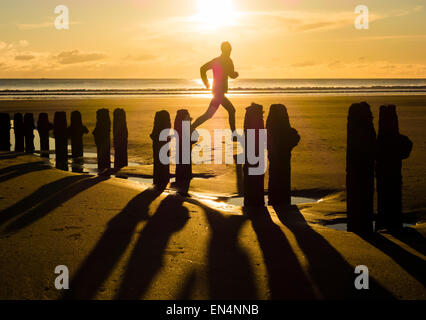 Uomo che corre sulla spiaggia al tramonto a Sandsend, North Yorkshire, Regno Unito. Foto Stock