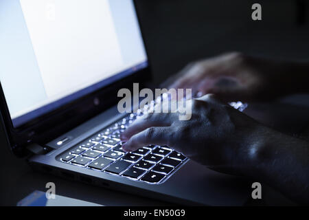 Hacker sul computer portatile in camera oscura Foto Stock