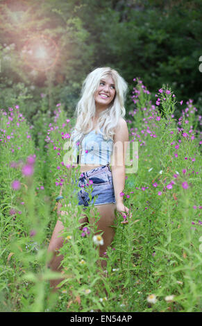 Bella giovane donna con capelli lunghi biondi in erba lunga Foto Stock