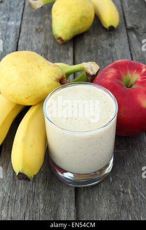 Frullato di bianco realizzato con apple, banana e pera su tavola di legno Foto Stock