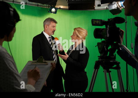 Femmina intervistando il presentatore in Studio televisivo con equipaggio in primo piano Foto Stock