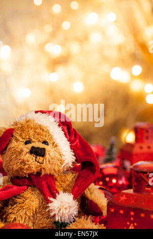 Un orsacchiotto di peluche vestito da Babbo Natale con un sfondo dorato Foto Stock