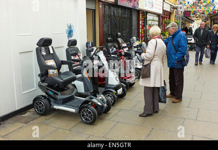 Coppia di anziani in cerca di mobilità scooter in Southport Foto Stock