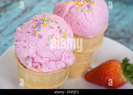 Gelato alla fragola con spruzza in waffle tazze contro di legno vintage sfondo, vista dall'alto Foto Stock