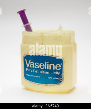 Vasca di vaselina vaselina contenente una siringa, isolato su sfondo bianco. Foto Stock