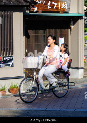 È comune vedere due persone in sella ad una bicicletta singolo in Giappone - in particolare di madri e bambini piccoli. Giapponese madre e bambino; figlia; bike. Foto Stock