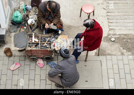 Un uomo la riparazione della suola di una calzatura clienti in Cina, Foto Stock