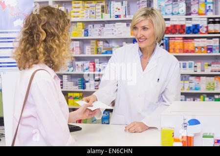 Il cliente consegna una prescrizione per un sorridente farmacista Foto Stock