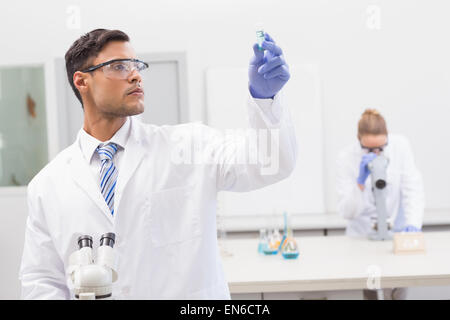 Scienziato esaminando precipitato blu nel tubo Foto Stock