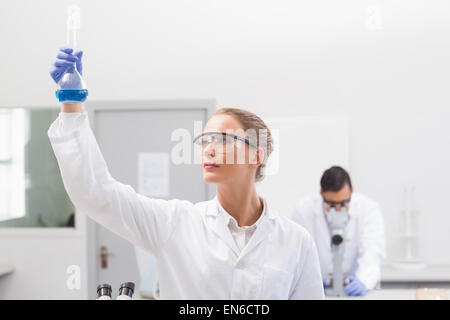 Scienziato esaminando precipitato blu in baker Foto Stock