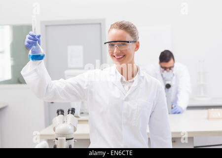 Scienziato esaminando precipitato blu in baker Foto Stock