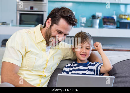 Padre e figlio utilizzando laptop sul lettino Foto Stock