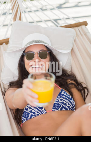 Bella bruna relax su una amaca e bere il succo d'arancia Foto Stock