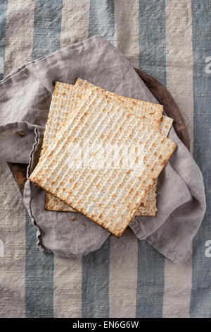 Matzah, il pane azzimo utilizzato nella festa ebraica pasqua, impostato sulla ciotola di legno in ambiente rustico Foto Stock