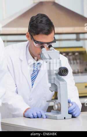 Scienziato esaminando qualcosa con il microscopio Foto Stock