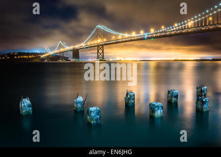 Pier palificazioni e il San Francisco - Oakland Bay Bridge di notte, a San Francisco, California. Foto Stock