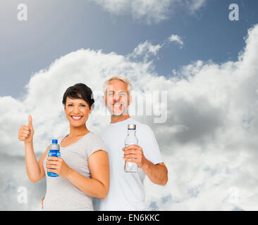 Immagine composita di montare giovane con bottiglie di acqua gesticolando pollice in alto Foto Stock