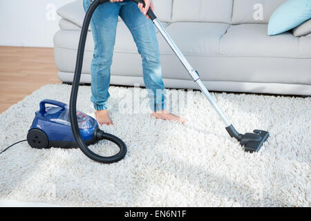 Donna che utilizza un aspirapolvere su un tappeto Foto Stock