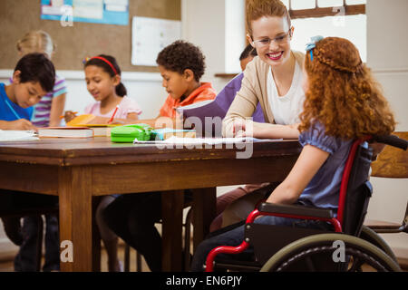 Docente aiutare una pupilla di disabili Foto Stock