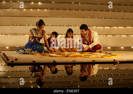 Famiglia disponendo diyas su rangoli Foto Stock