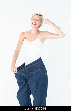 Donna sorridente indossando troppo jeans grandi Foto Stock