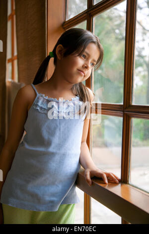 Bambina guardando fuori della finestra Foto Stock