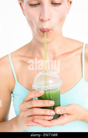 Attraente bionda di bere succo verde Foto Stock