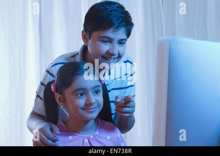 Ragazzo puntando qualcosa alla ragazza sul computer Foto Stock