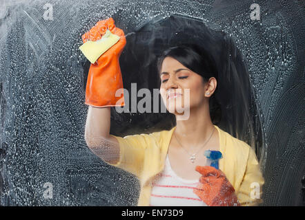 Giovane donna pulizia di una finestra Foto Stock