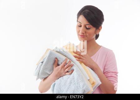 Giovane donna tenendo un mucchio di asciugamani Foto Stock