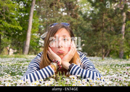 Bruna ragazza distesa in erba pieno di fiori Foto Stock