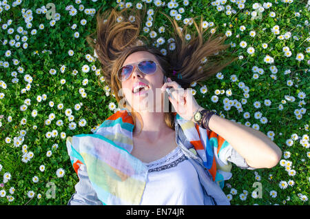 Brunette girl parlando al telefono nel prato circondato da fiori Foto Stock