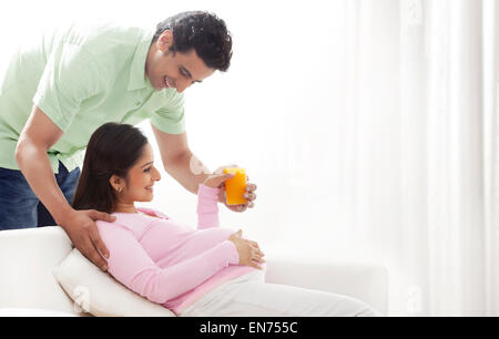 L'uomo che la donna incinta di succo d'arancia Foto Stock