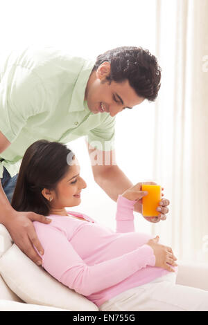 L'uomo che la donna incinta di succo d'arancia Foto Stock