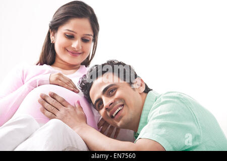 Uomo che ascolta moglie incinta stomaco Foto Stock