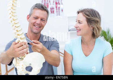 Fisioterapista che mostra il modello della colonna vertebrale per il suo paziente Foto Stock