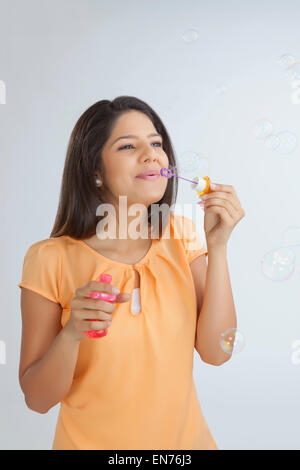 Giovane donna soffiando bolle di sapone Foto Stock