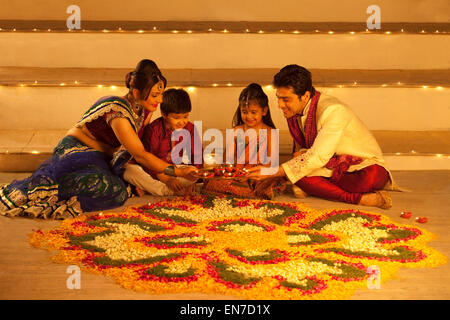 Famiglia disponendo diyas su rangoli Foto Stock