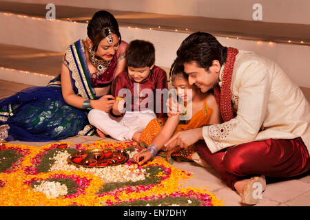 Famiglia disponendo diyas su rangoli Foto Stock