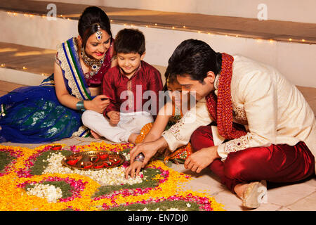 Famiglia disponendo diyas su rangoli Foto Stock