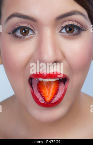 Ritratto di una donna con una fettina di fragola sulla sua lingua Foto Stock