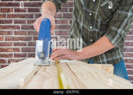 Immagine composita di carpenter il taglio di tavolato in legno con sega elettrica Foto Stock