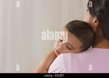 Il bambino dorme sulla spalla delle madri Foto Stock