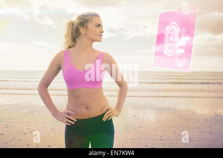 Immagine composita della tonica donna con le mani sui fianchi sulla spiaggia Foto Stock