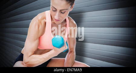 Immagine composita della donna forte facendo bicipite curl con manubrio blu Foto Stock