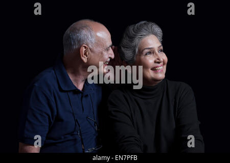 Il vecchio uomo whispering in womans orecchio Foto Stock