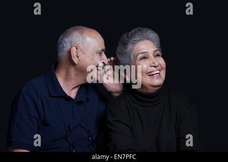 Il vecchio uomo whispering in womans orecchio Foto Stock