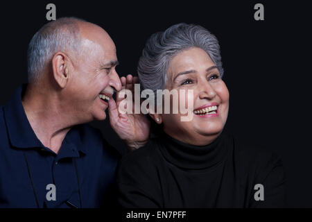 Il vecchio uomo whispering in womans orecchio Foto Stock