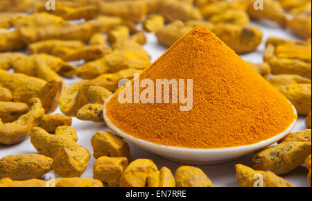 Close up di curcuma in polvere in una ciotola e curcuma radici Foto Stock